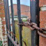 a rusted iron gate with a chain hanging from it