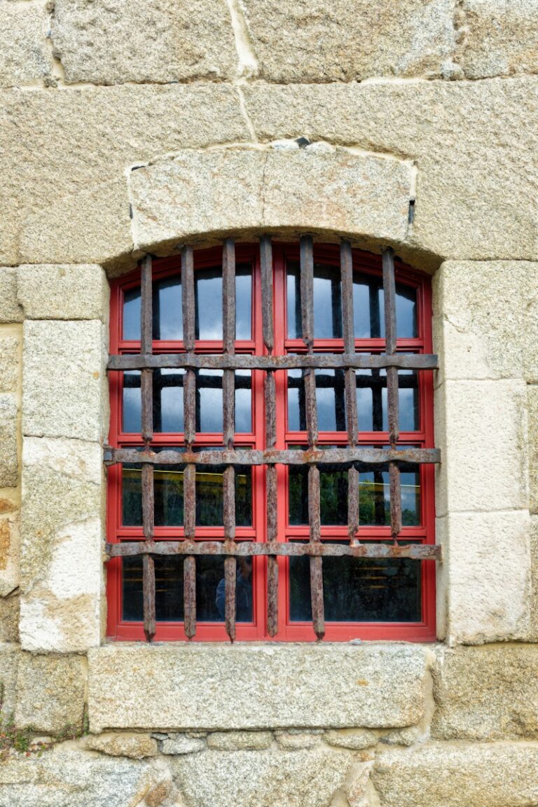a red window with bars on a stone wall